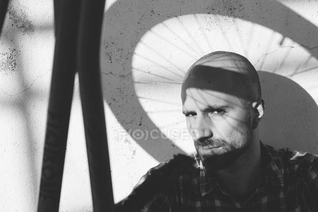 Hombre con sombra de rueda de bicicleta en la cara - foto de stock
