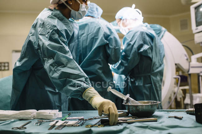 Chirurgo che prende strumento chirurgico dal tavolo — Foto stock