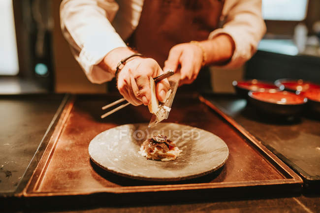 Cozinheiros mãos esfregando queijos no prato — Fotografia de Stock