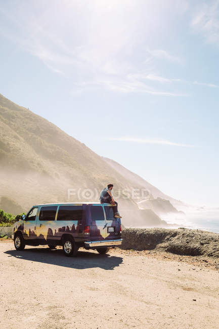 Мужчина сидит на крыше фургона — стоковое фото