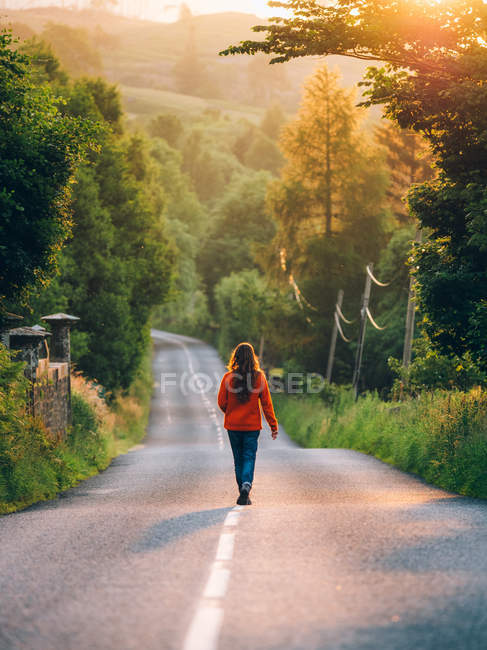 Menina caminhando ao longo da estrada rural — Fotografia de Stock