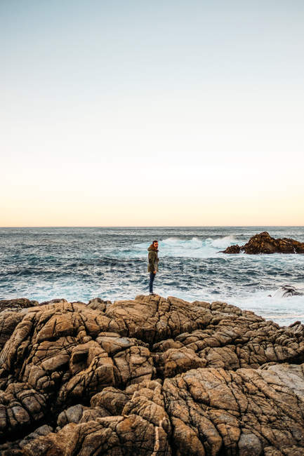 Человек, стоящий на скалистом берегу — стоковое фото
