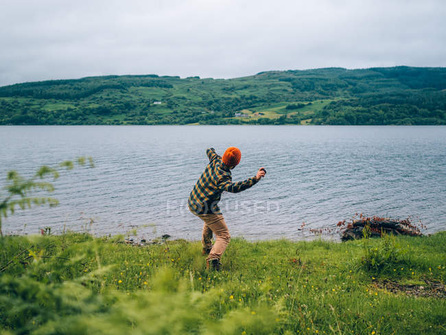 Хлопчик кидає камінь у воду — стокове фото