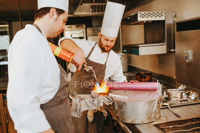 Cozinheiros usando queimador para fumar prato — Fotografia de Stock
