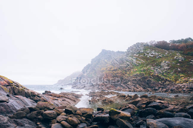 Foggy mountain on shore — Stock Photo