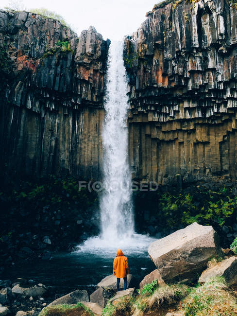 Людина стоїть проти потужного водоспаду — стокове фото