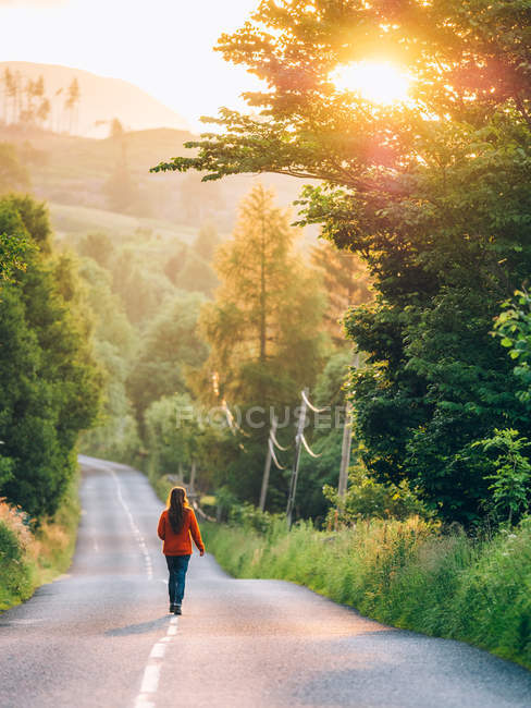 Fille marche route rurale tandis que le coucher du soleil — Photo de stock