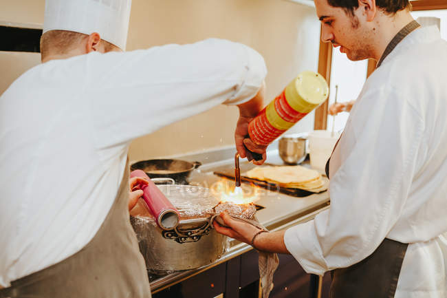 Köche benutzen Taschenlampe, um Essen zu räuchern — Stockfoto