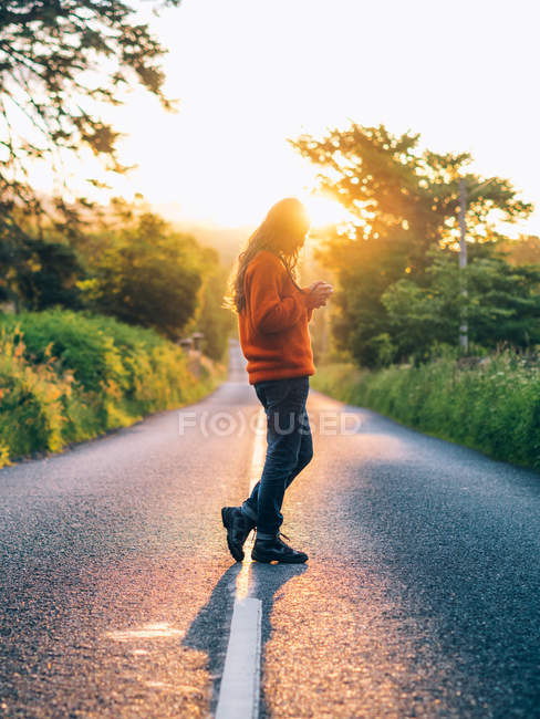 Chica en camino rural mientras atardecer - foto de stock