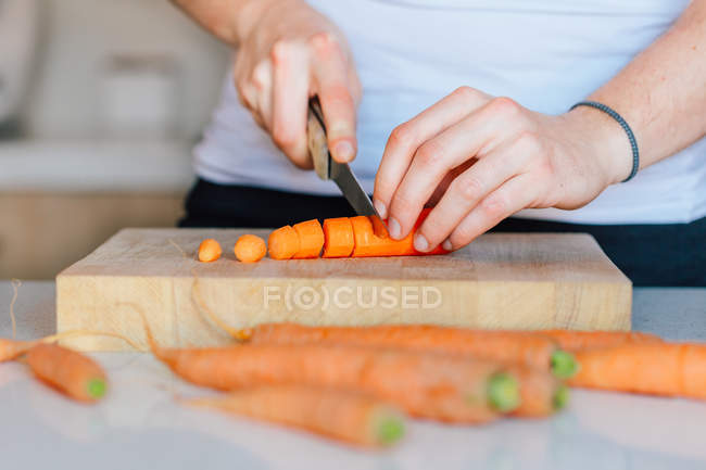 Руки нарізають моркву на дошці — стокове фото