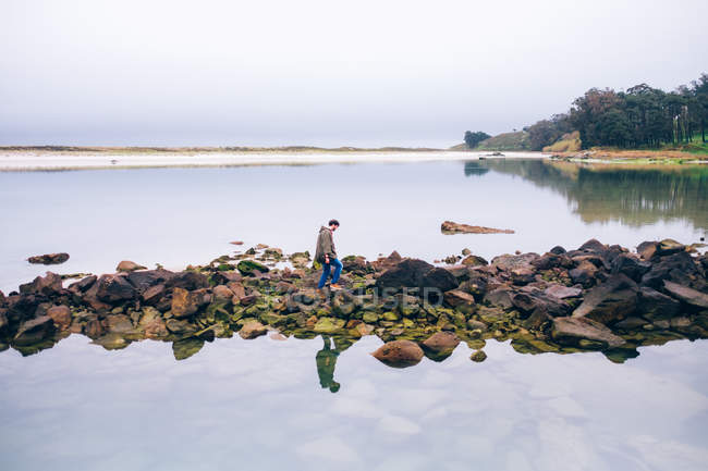 Mann läuft auf Felsbrocken am Ufer — Stockfoto