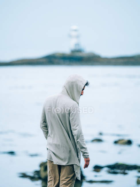 Hombre de pie sobre el paisaje marino borroso - foto de stock