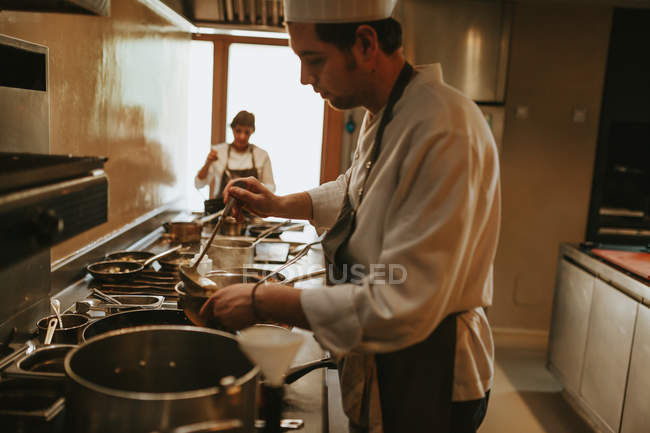 Koch gießt Suppe — Stockfoto