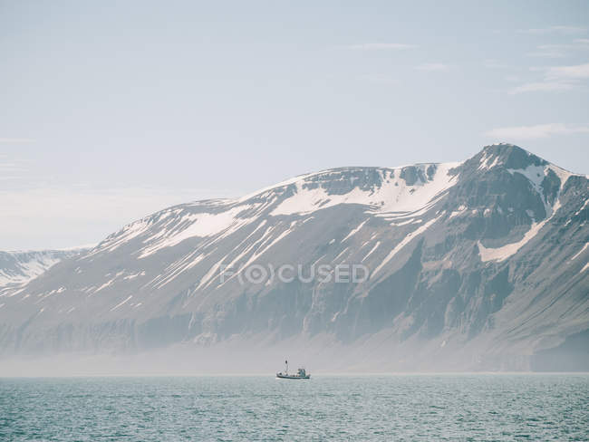 Barco flotando contra montañas nevadas - foto de stock