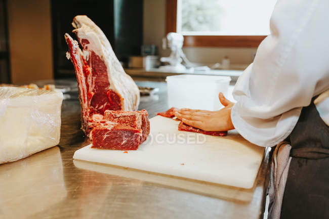 Cooks hands slicing meat — Stock Photo