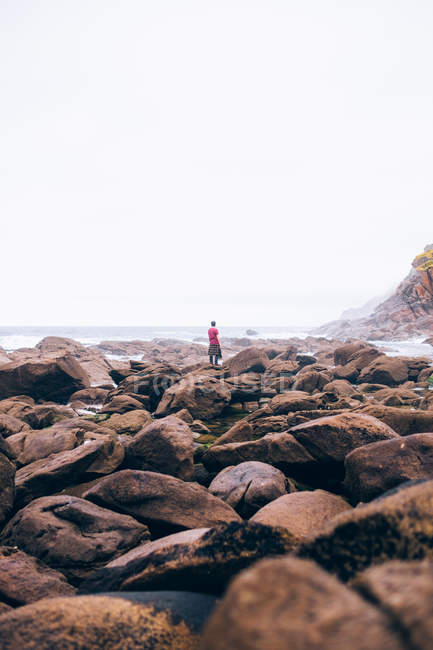 Человек, стоящий на берегу валунов — стоковое фото