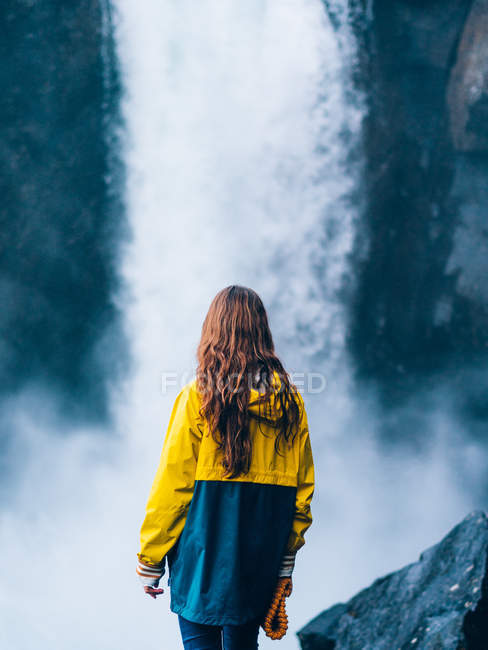 Girl standing against waterfal — Stock Photo