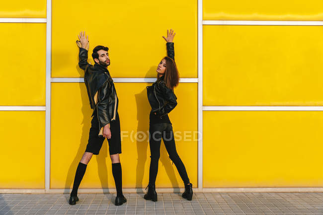 Модна пара позує над жовтою стіною — стокове фото