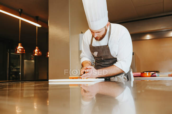 Cook slicing ingridients on board — Stock Photo