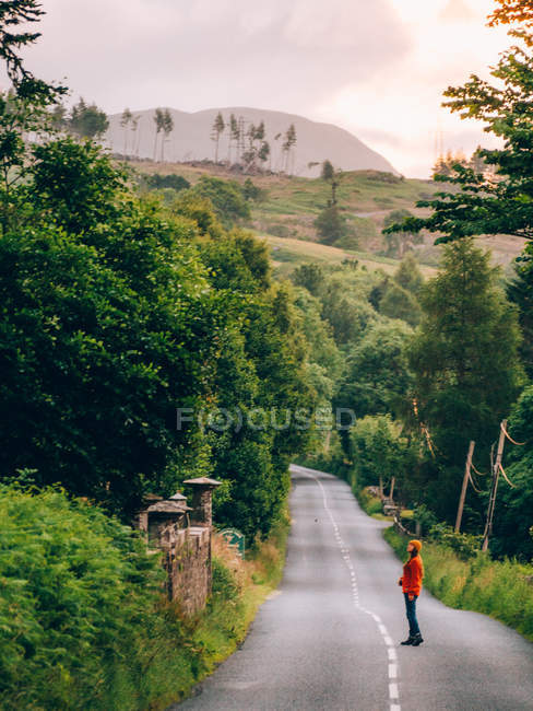 Menina na estrada rural olhando para cerca — Fotografia de Stock