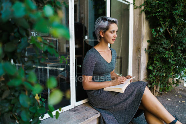 Жінка читає книгу у вікні — стокове фото