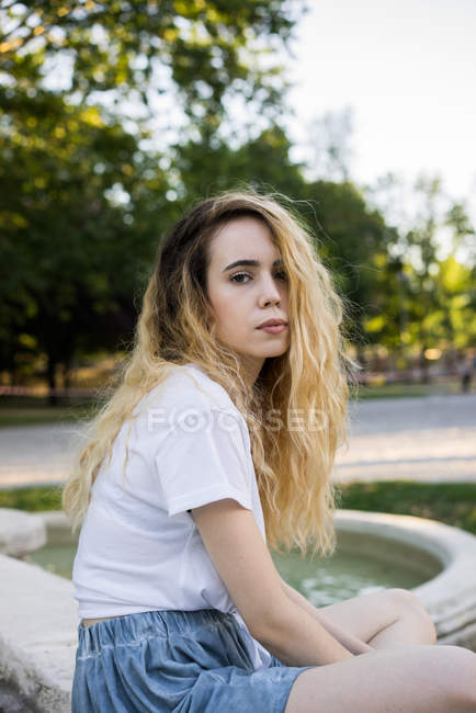 Adolescent posant sur le côté de fontaines — Photo de stock