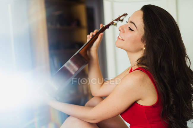 Smiling brunette posing with small guitar — Stock Photo