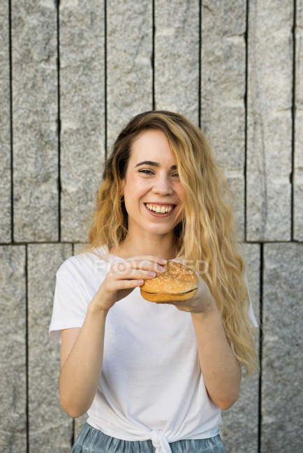 Smiling girl eating hamburger — Stock Photo