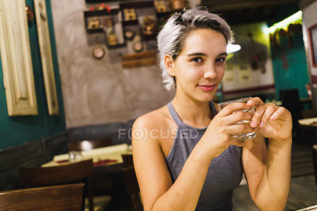 Young woman with drink in bar — Stock Photo