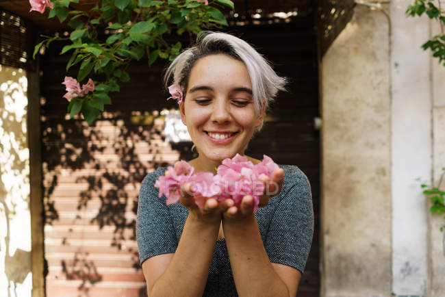 Woman blowing petals from hands — Stock Photo