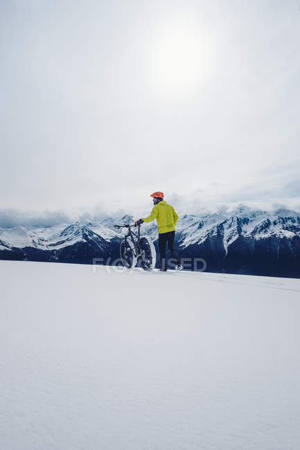 Uomo con bici sulle montagne invernali — Foto stock