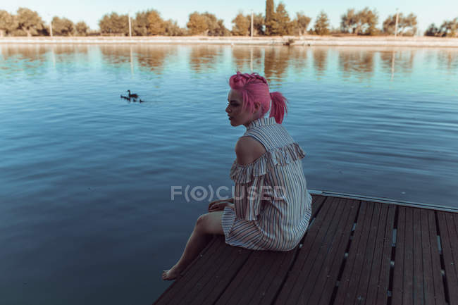 Fille assise sur la jetée du lac — Photo de stock