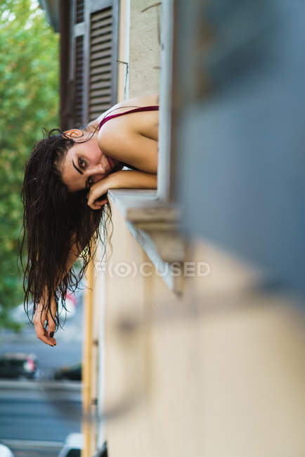 Jovem mulher se curvando pela janela — Fotografia de Stock
