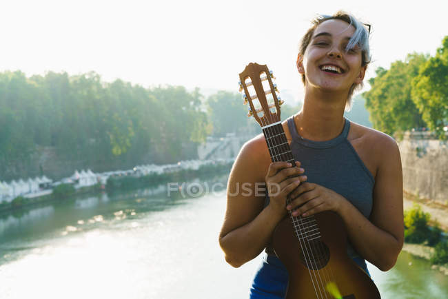 Девушка позирует с маленькой гитарой на улице — стоковое фото