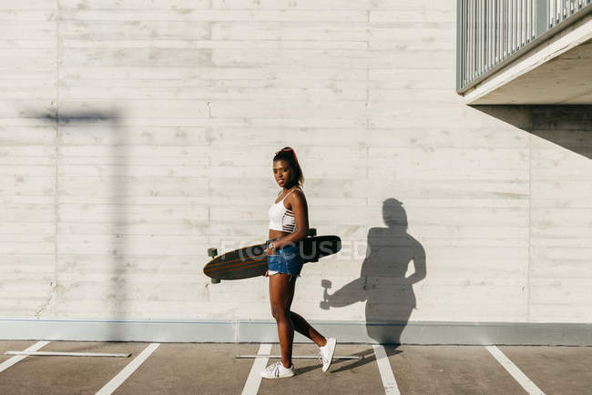 Stilvolle Frau mit Brett läuft auf Straße — Stockfoto