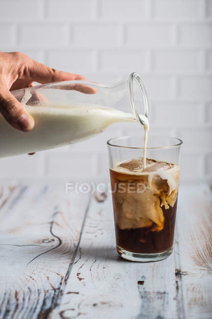 Pouring milk iced coffee — Stock Photo
