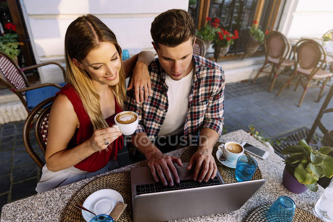 Happy couple at coffee shop using laptop. — Stock Photo
