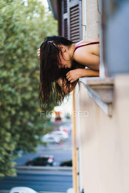 Mujer joven doblando por la ventana - foto de stock