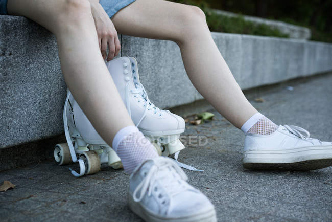 Crop girl en baskets avec patins à roulettes — Photo de stock