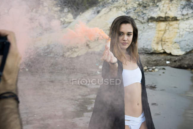Дівчина з кольоровим димом на пляжі — стокове фото