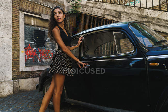 Женщина возле ретро-машины на улице — стоковое фото