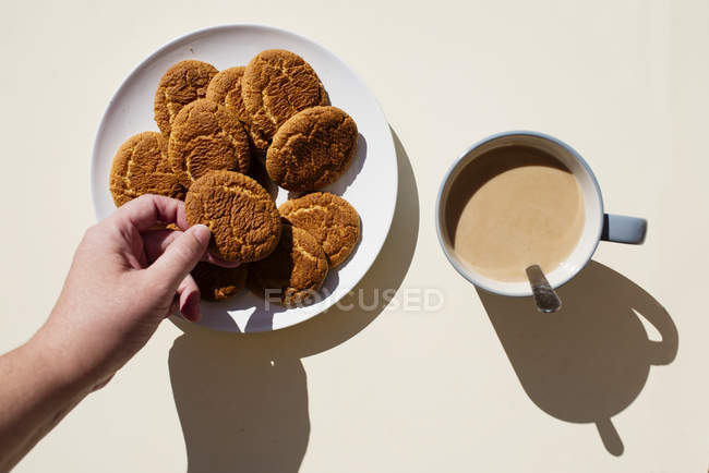 Hand taking cookies from plate — Stock Photo