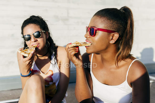 Young girls eating pizza outdoors — Stock Photo