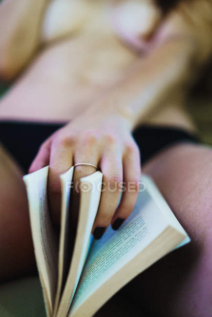 Crop femme avec livre entre les jambes — Photo de stock