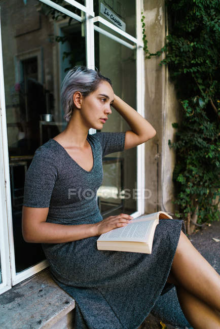 Жінка читає книгу у вікні — стокове фото
