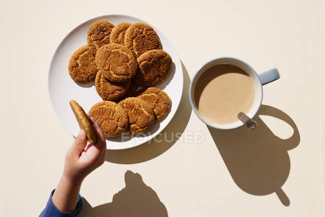 Mão tomando biscoitos de prato — Fotografia de Stock