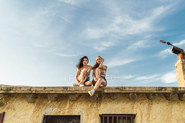 Pretty women sitting on roof — Stock Photo