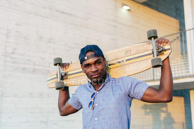 Stylischer schwarzer Mann posiert mit langem Brett — Stockfoto