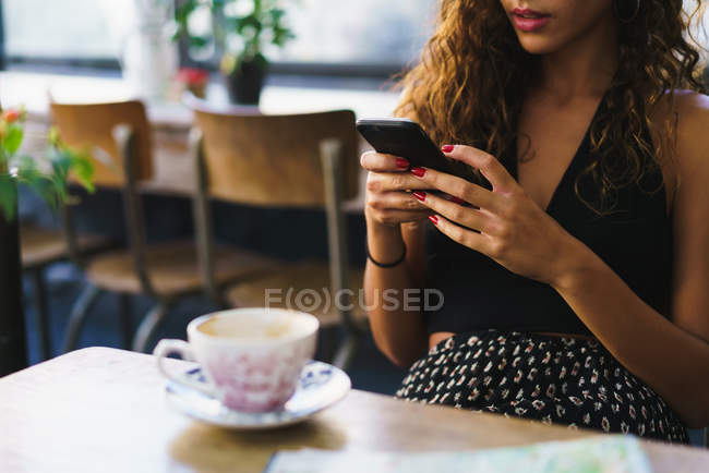 Crop girl in cafe with phone — Stock Photo