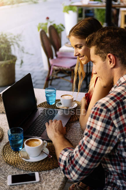 Coppia felice in caffetteria utilizzando il computer portatile . — Foto stock